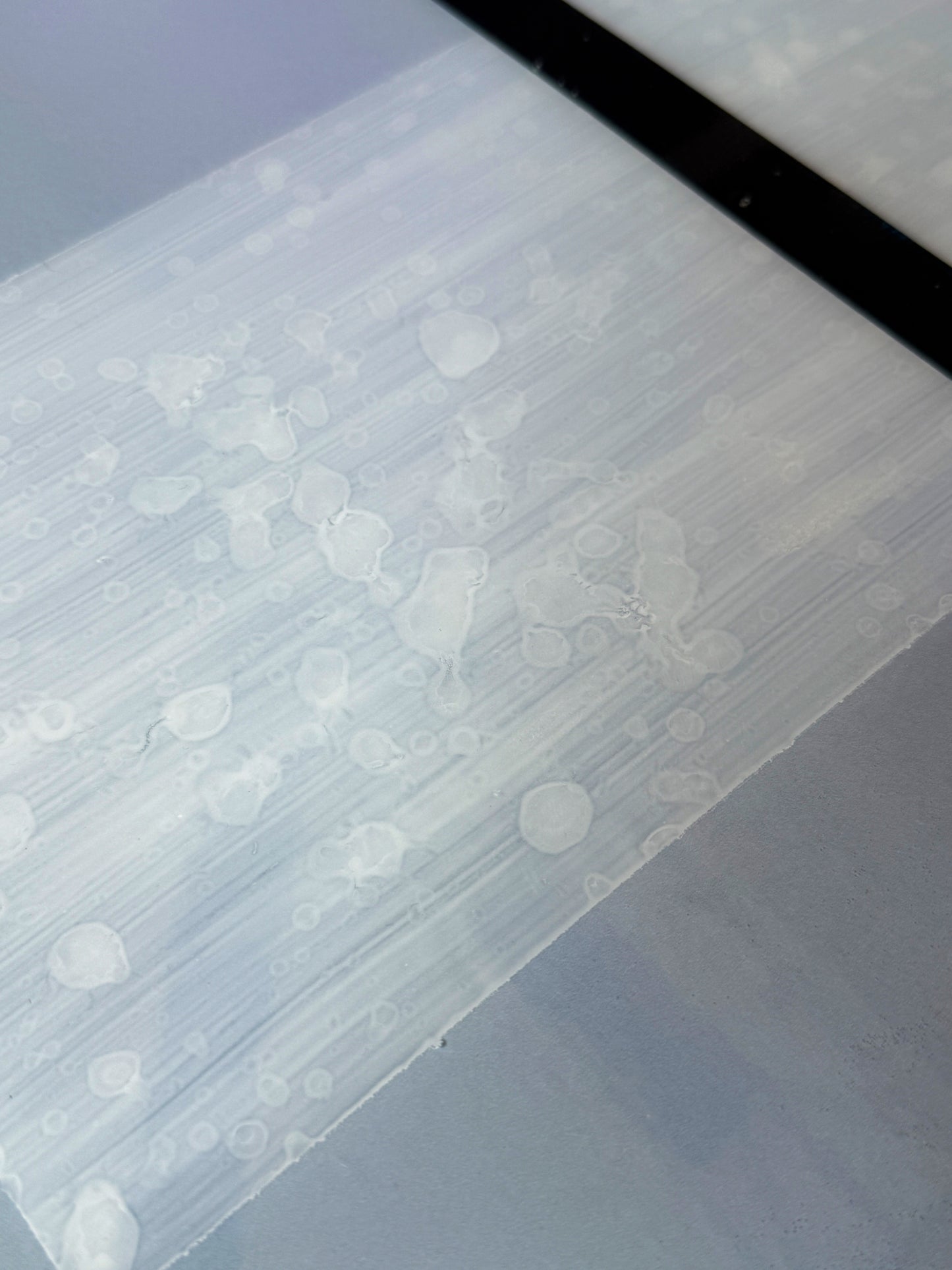 Close-up of resin texture on 'Alaskan Mist' mixed media artwork by Christen Oatley, highlighting layered acrylic and oil elements beneath a glassy resin surface with organic bubble patterns and fine brushstroke details.