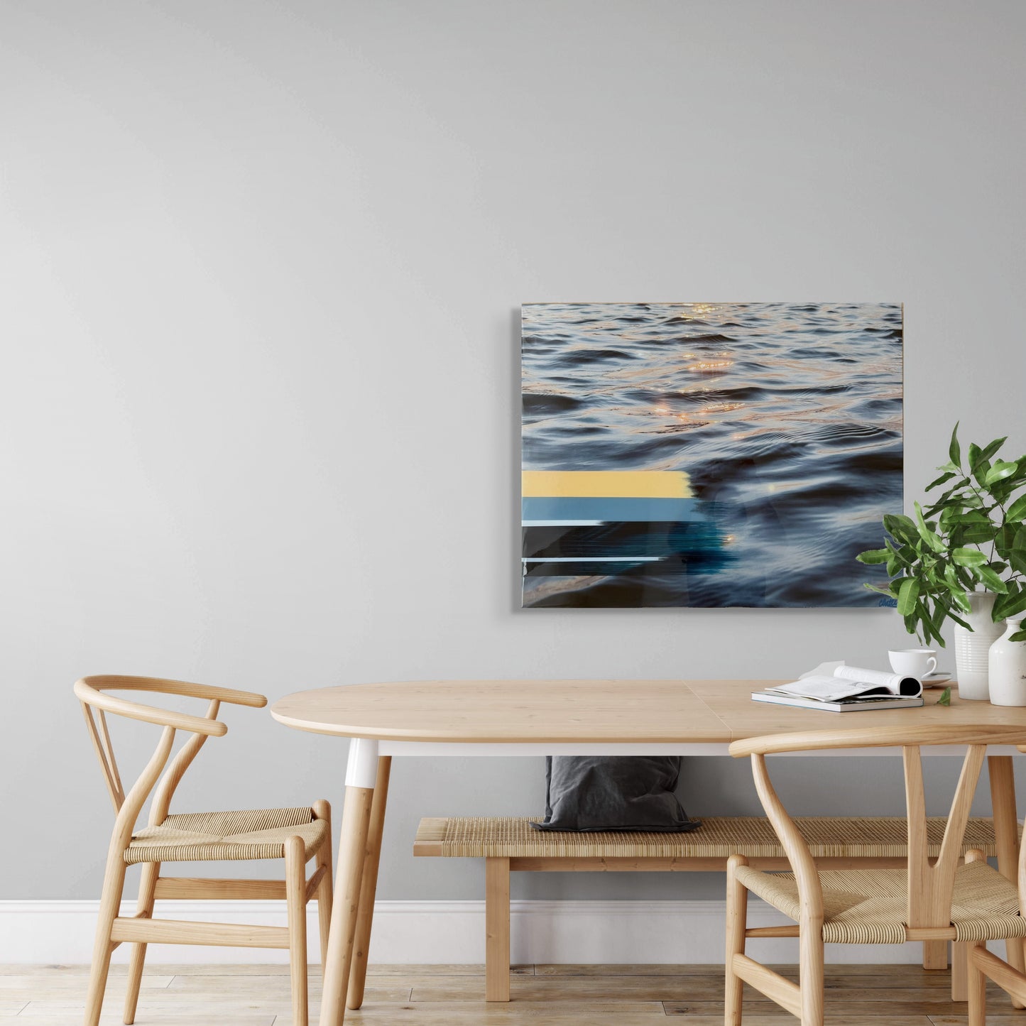 'Sunset Tones' by Christen Oatley displayed above a minimalist dining table, original mixed media artwork with lake reflections and resin finish on birchwood panel, styled in a modern home interior.