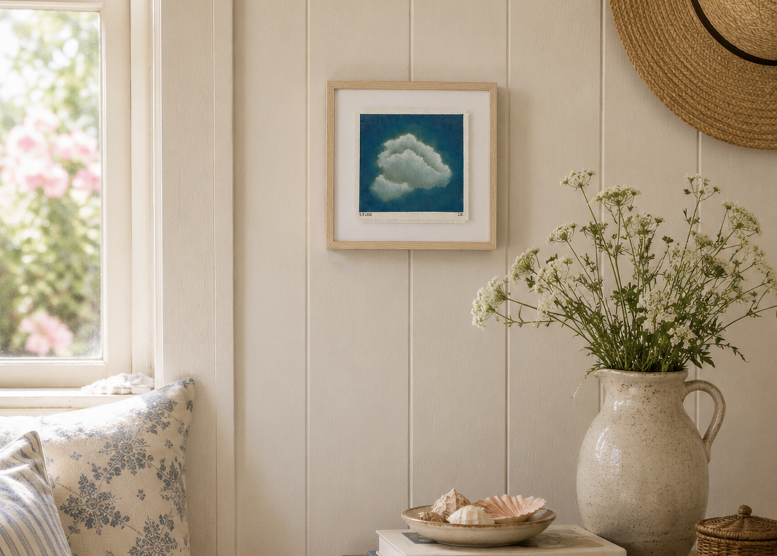 Cozy living room with a window, framed artwork, and decorative items on a table.