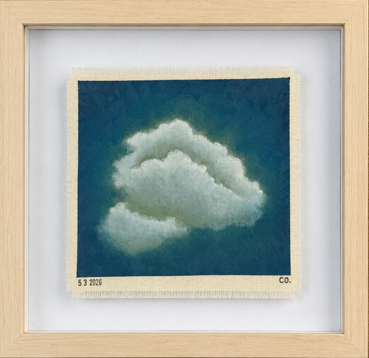 Framed artwork of a cloud on a wooden surface